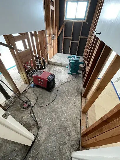 Hallway with opened walls and ceiling, a red dehumidifier and air movers drying it