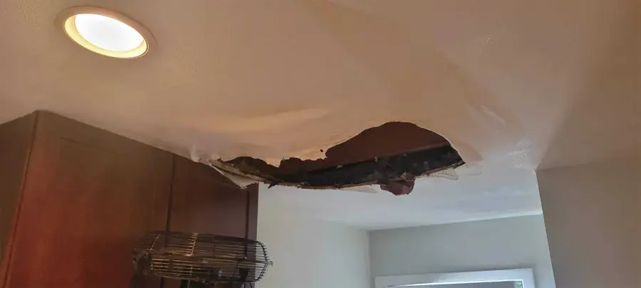 Kitchen ceiling drywall torn open by a leak from above