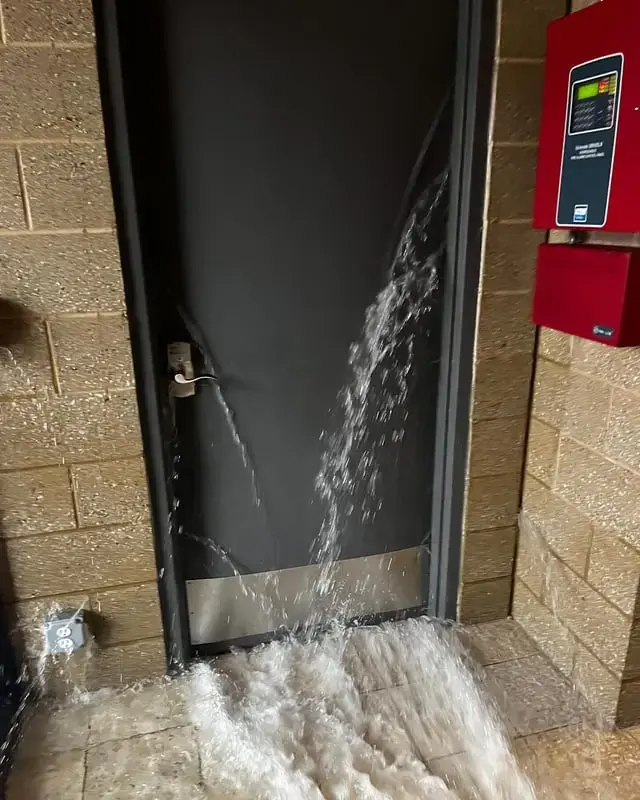 Water pouring under a commercial service door from a failed pipe