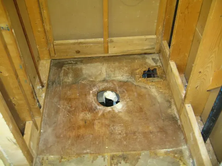 Shower pan removed to show a water-damaged subfloor and framing