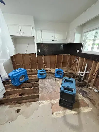 Air movers and a dehumidifier drying an opened kitchen after a water loss
